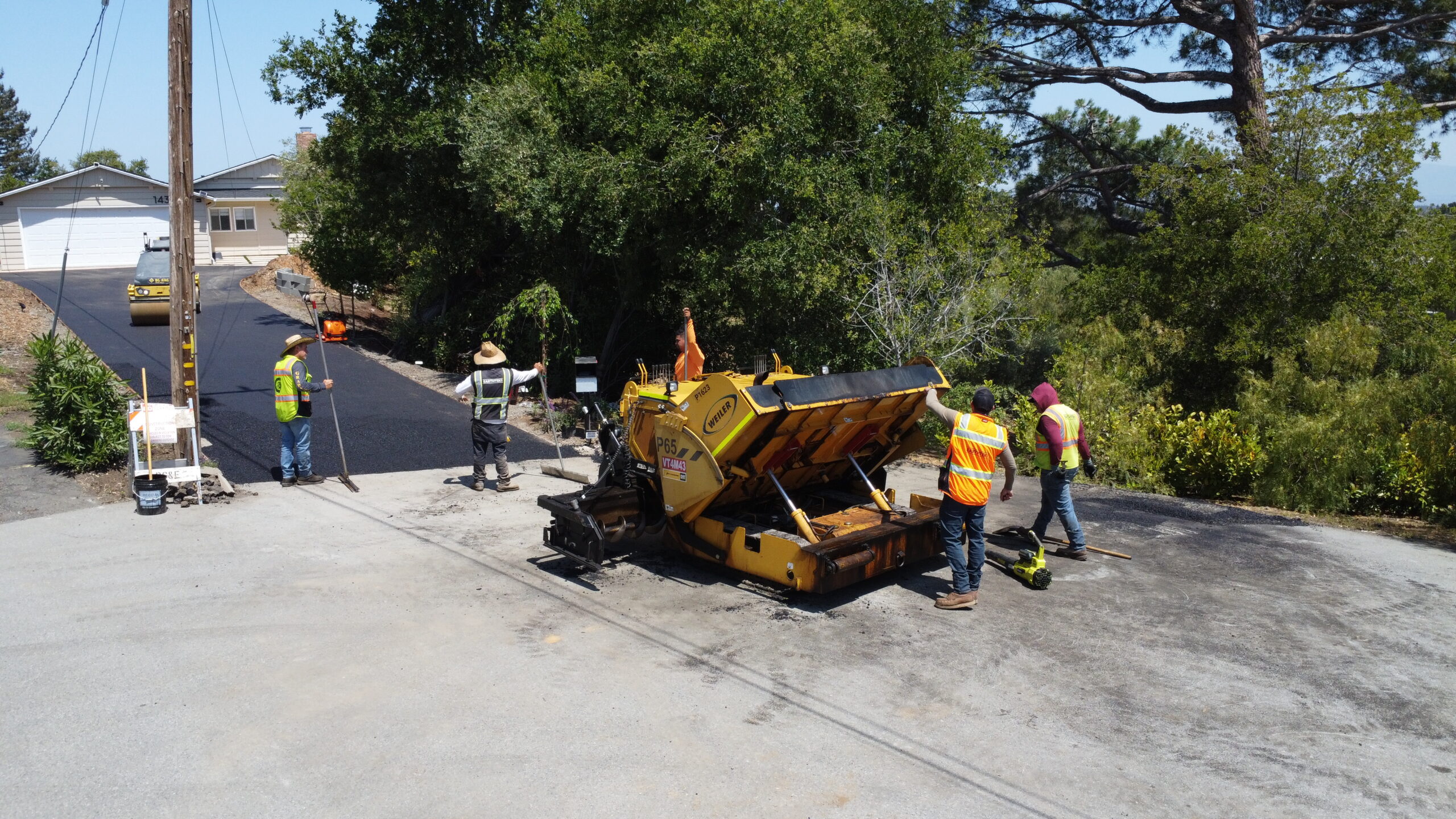 crew and paver placing asphalt on the slope